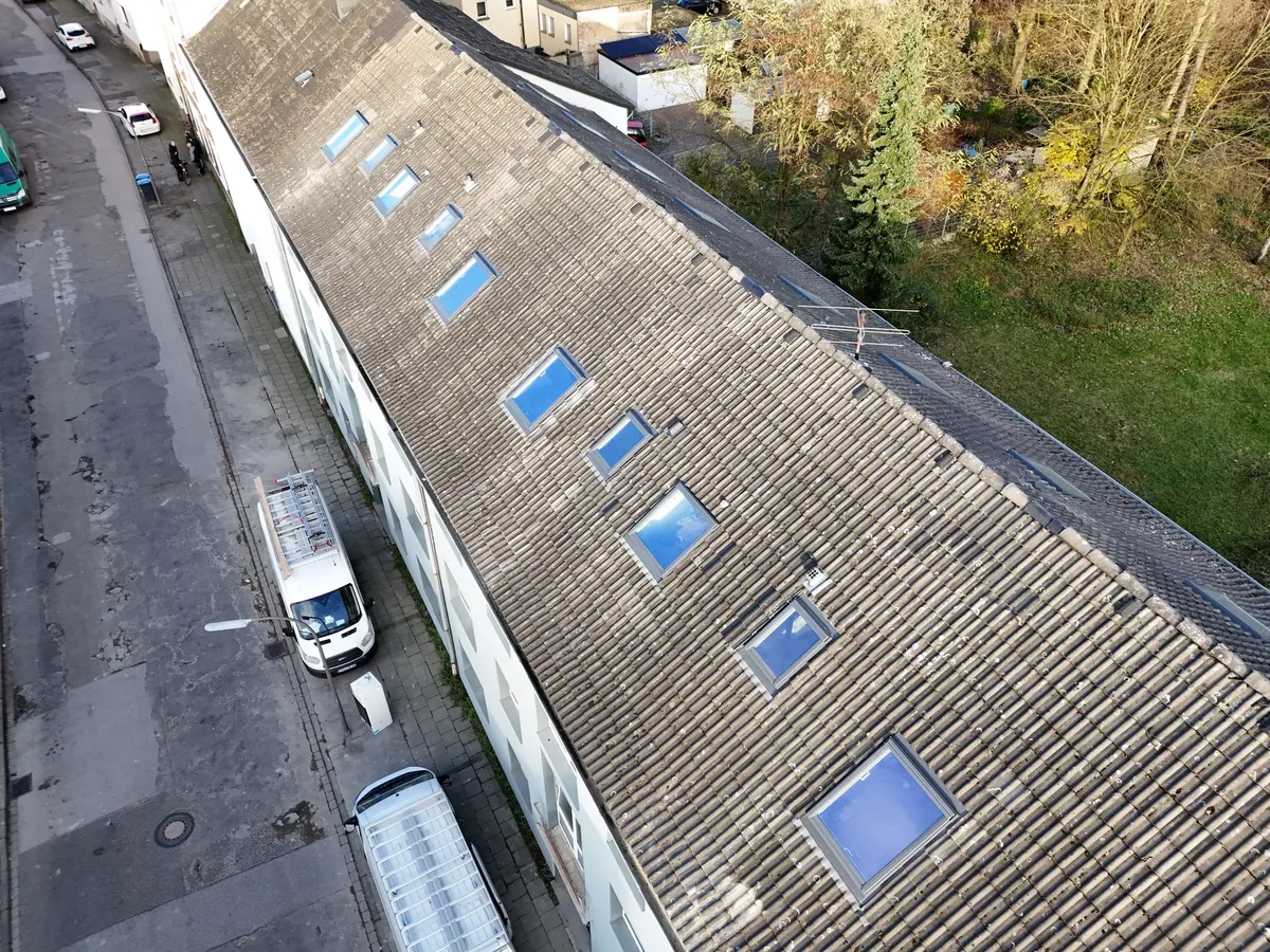 Steildach mit mehreren neu eingebauten Dachfenstern in einer Reihe, Aufnahme aus der Luft