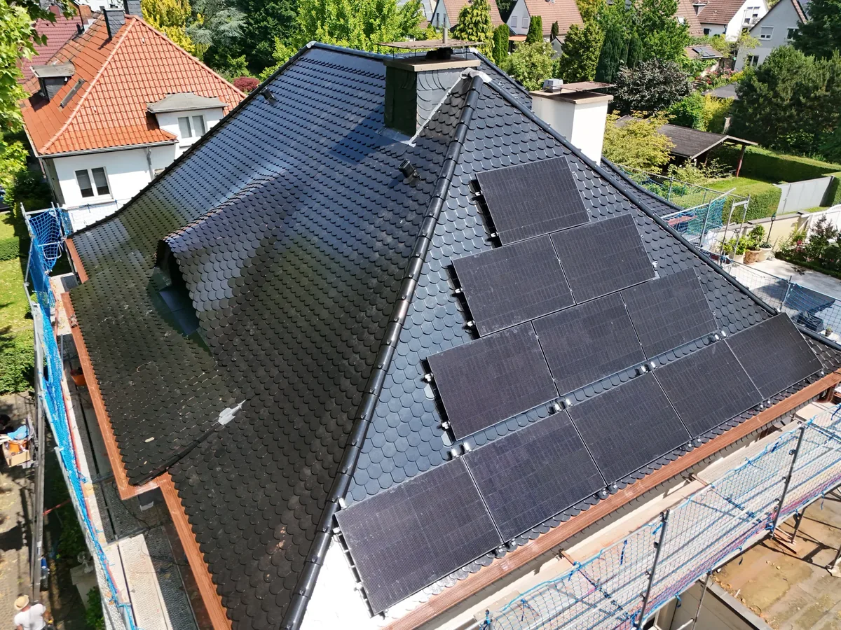 Saniertes Walmdach mit dunkler Eindeckung und Aufdach-Photovoltaikanlage in Herne aus der Luft