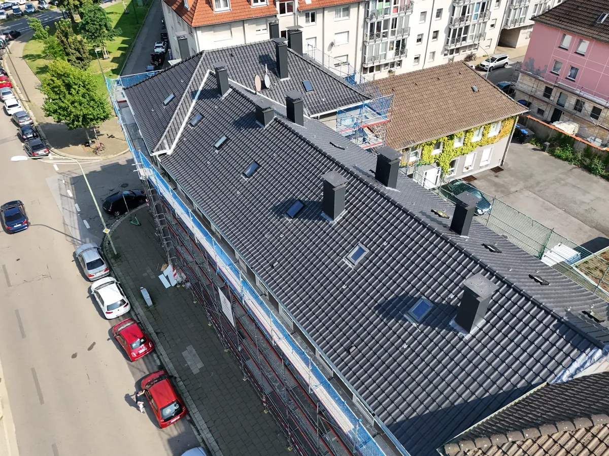 Neu eingedecktes Satteldach eines Mehrfamilienhauses in Essen aus der Luft, anthrazitfarbene Ziegel mit Gauben