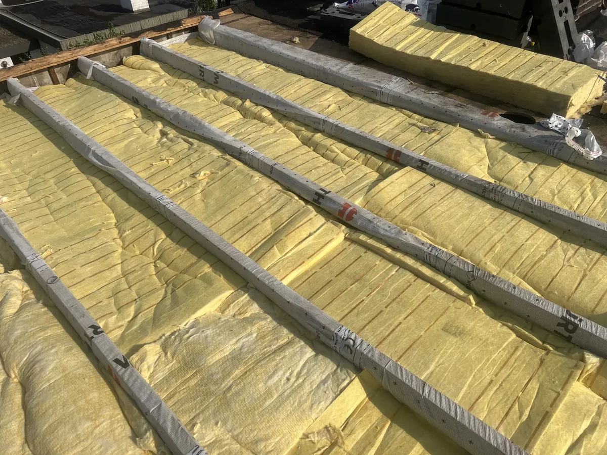 Zwischensparrendämmung mit gelber Mineralwolle und verklebter Dampfbremsfolie im offenen Dachstuhl
