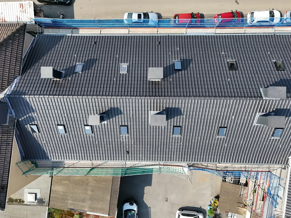 Neu eingedecktes Dach eines Mehrfamilienhauses in Essen mit anthrazitfarbenen Ziegeln, Luftaufnahme